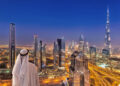 Arabian man watching night cityscape of Dubai with modern futuri